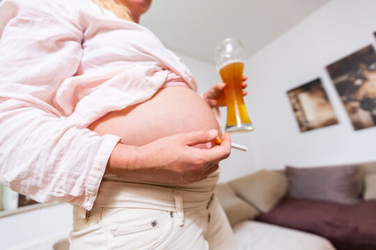 a pregnant woman with a beer and a cigarette in her hand