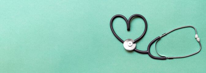 Stethoscope in Shape of Heart Isolated On Green Background. Banner. Copy space. Place for text.