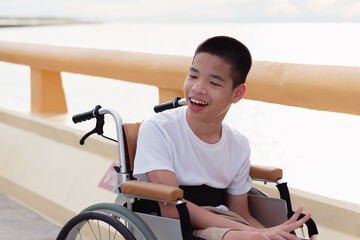 Obraz premium Disabled child on wheelchair is smiling, playing, learning in the outdoor nature park like other people,Lifestyle of special child, Life in the education age of children, Happy disability kid concept.