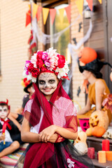 Cheerful girl with painted face looking at you with smile against her friends