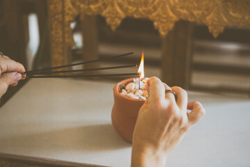 Buddhist temple at Santa Teresa, Rio de Janeiro, Brazil. Hand lighting up incense on a candle inside a small pottery vase.