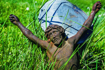 The crucifixion of Jesus Christ. Close up very old and ancient statue in the grass. Horizontal image.