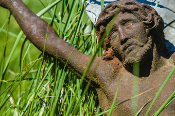 The crucifixion of Jesus Christ. Very old and ancient statue in the grass.