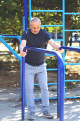 Senior man on the street goes in for sports on the playground.