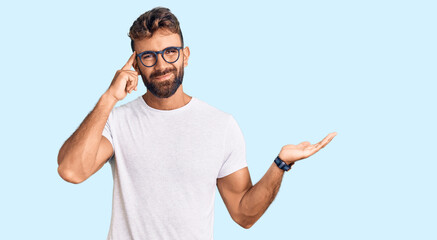 Young hispanic man wearing casual clothes and glasses confused and annoyed with open palm showing...