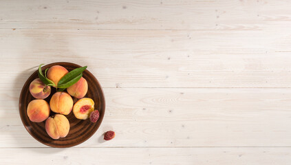 A large banner with peaches on a whitewashed wooden background. The peaches are on a brown clay plate. The view from the top