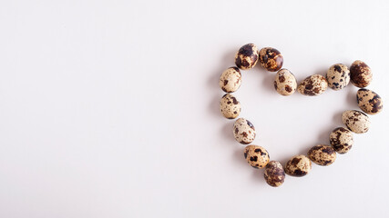 Shape of heart from the quail of eggs on white background. Text space.  Top view