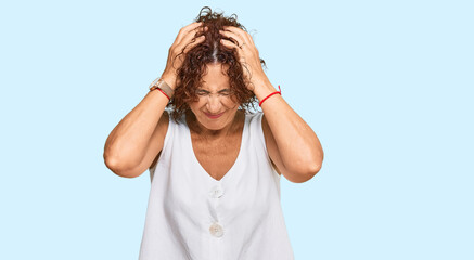 Beautiful middle age mature woman wearing casual white shirt suffering from headache desperate and stressed because pain and migraine. hands on head.