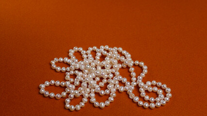 There is a pearl necklace on a yellow background. Beads from white large pearls.