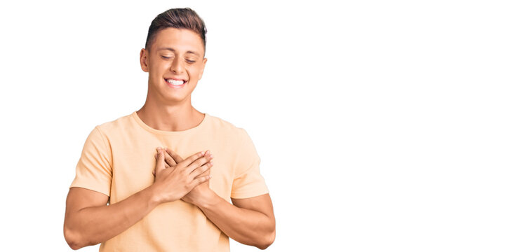 Young handsome man wearing casual clothes smiling with hands on chest with closed eyes and grateful gesture on face. health concept.