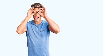 Young handsome man wearing casual clothes doing ok gesture like binoculars sticking tongue out, eyes looking through fingers. crazy expression.