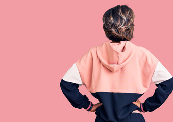 Young beautiful woman wearing sportswear standing backwards looking away with arms on body