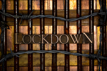 Lockdown text formed by real authentic typeset letters on vintage textured rusty grunge nails with barbed wire on bronze copper and gold background