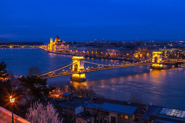 Fototapeta na wymiar Twilight over the city of Budapest. Seen is the Danube River and the illuminated Hungarian Parliament building and the Chain Bridge