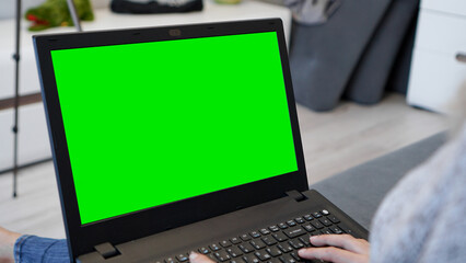 Woman using laptop with green screen. Woman typing on a laptop keyboard. Business, communication, freelance and internet concept