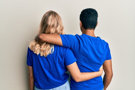 Young interracial couple wearing casual clothes hugging oneself happy and positive from backwards. self love and self care