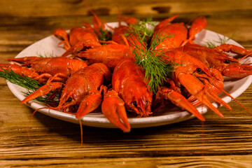 Plate with boiled crayfishes on wooden table
