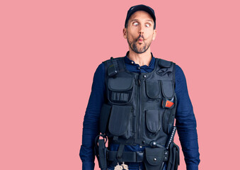 Young handsome man wearing police uniform making fish face with lips, crazy and comical gesture. funny expression.