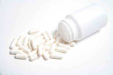 white plastic tube without inscriptions from pills on a white background and white pills near