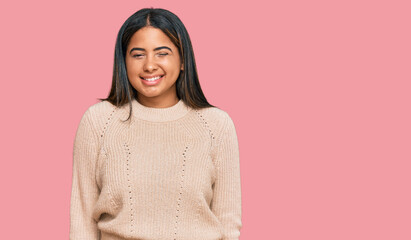 Young latin girl wearing wool winter sweater winking looking at the camera with sexy expression,...