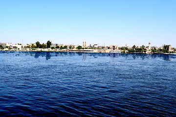 The clear sky and the reflection of the city on the surface of the water What is the most beautiful view of this city. Please zoom in on the image, see the city