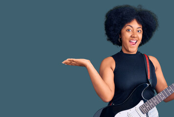 Young african american girl playing electric guitar celebrating victory with happy smile and winner expression with raised hands