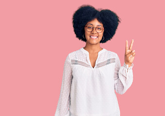 Young african american girl wearing casual clothes smiling with happy face winking at the camera doing victory sign. number two.