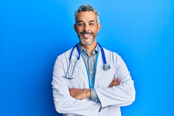 Middle age grey-haired man wearing doctor uniform and stethoscope happy face smiling with crossed...