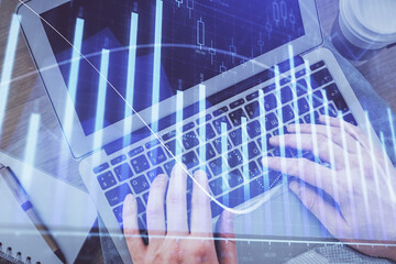 Fototapeta na wymiar Double exposure of man's hands typing over computer keyboard and forex graph hologram drawing. Top view. Financial markets concept.