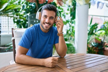 Young hispanic man listening to music using headphones at the terrace.