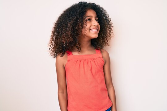 African American Child With Curly Hair Wearing Casual Clothes Looking To Side, Relax Profile Pose With Natural Face And Confident Smile.