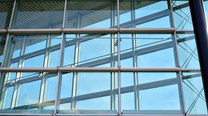 Blue curtain wall made of toned glass and steel constructions under blue sky. A fragment of a building.