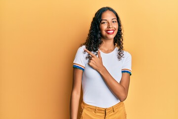 Young african american girl wearing casual clothes cheerful with a smile of face pointing with hand and finger up to the side with happy and natural expression on face