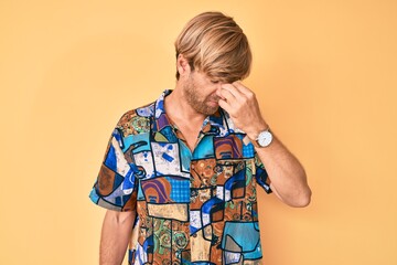 Young blond man wearing summer shirt tired rubbing nose and eyes feeling fatigue and headache....