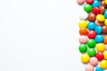 Colored balls of sugar on a white background. Chocolate candies covered with multicolored sugar glaze. Place for text