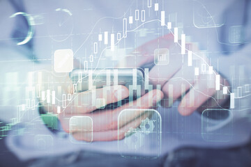 Double exposure of man's hands holding and using a digital device and forex graph drawing. Financial market concept.