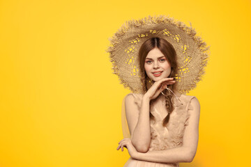 Emotional girl in a straw hat and a dress on a yellow background with red pigtails Copy Space