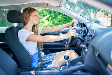 Young beautiful blonde woman smiling happy driving car