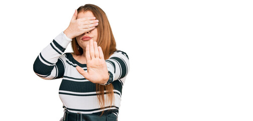 Young beautiful redhead woman wearing elegant clothes covering eyes with hands and doing stop gesture with sad and fear expression. embarrassed and negative concept.
