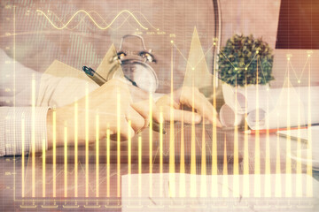 Double exposure of man's hands holding and using a phone and financial graph drawing. Analysis concept.