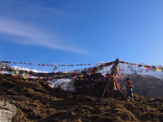 A climber staring at Talcho (Tibetan praying flags) under a blue sky, ABC (Annapurna Base Camp) Trek, Annapurna, Nepal