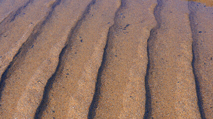 Sandy beach at low tide, natural ripple sand patterns. 
Low sun creating beautiful highlighted shapes and shadow 