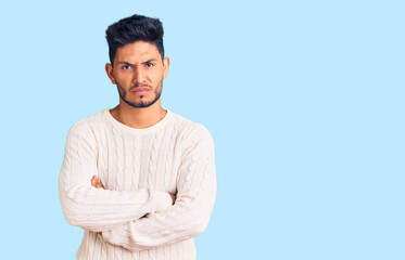 Handsome latin american young man wearing casual winter sweater skeptic and nervous, disapproving...