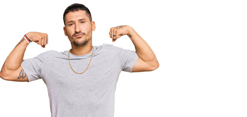 Handsome man with tattoos wearing 90s style showing arms muscles smiling proud. fitness concept.