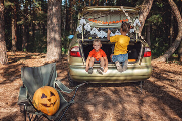 Safe distant Halloween celebration. Kids preparing decoration for party in the trunk of car