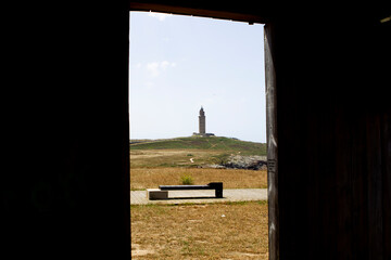 View of the Tower of Hercules framed in a wooden window located opposite