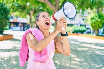 Middle age sportswoman screaming using megaphone at the park