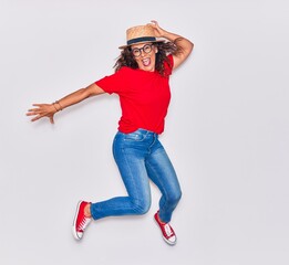 Middle age beautiful hispanic woman wearing casual clothes and hat smiling happy. Jumping with smile on face over white background