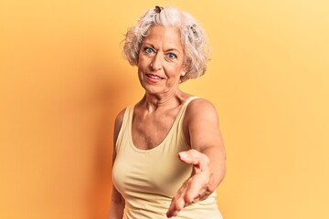 Senior grey-haired woman wearing casual clothes smiling cheerful offering palm hand giving assistance and acceptance.