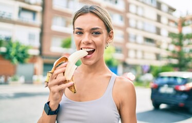 Young cauciasian fitness woman wearing sport clothes training outdoors eating healthy banana for strength and energy
